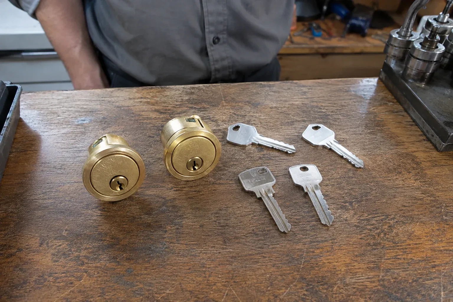 Two detached brass lock cylinders and four house keys on a wooden counter. — Lock Rekeying, Welland