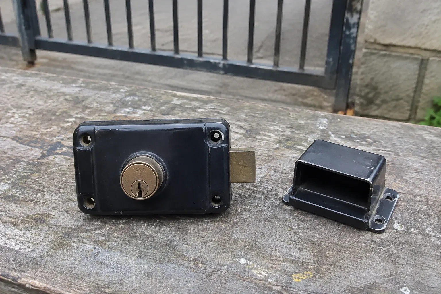 Detached rim gate lock and separate box keeper on an outdoor workbench. — Gate & Building Entry Locks, Welland